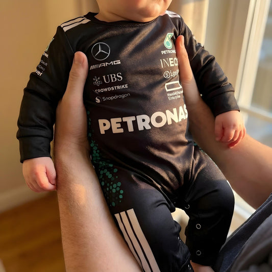 parent holding a baby wearing a mercedes formula one baby onesie