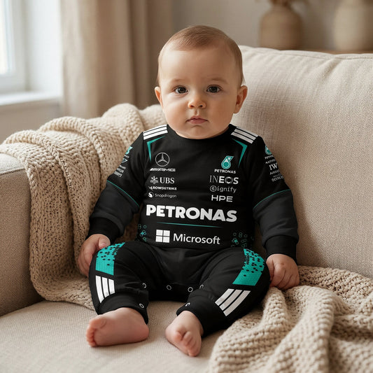 Baby in Mercedes AMG F1 long-sleeve race suit romper with PETRONAS teal accents and INEOS UBS sponsor logos on beige sofa