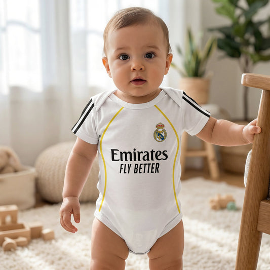 baby wearing Real Madrid 2025-26 white bodysuit standing in bright nursery holding wooden crib rail