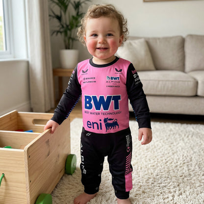 Toddler standing in Alpine 2025 F1 baby onesie pink and black with BWT and eni logos in living room