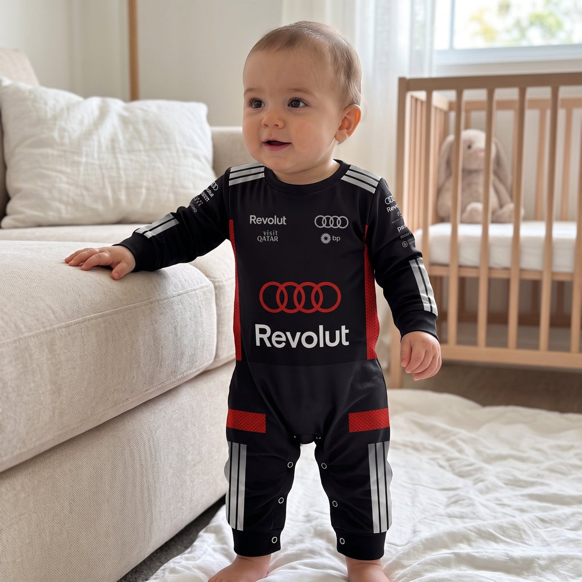 Baby wearing Audi 2026 racing onesie standing in nursery front view with Audi rings and Revolut logo