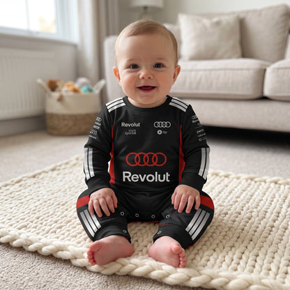 Baby sitting on blanket wearing Audi 2026 racing onesie smiling with Audi rings and Revolut logo