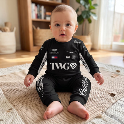 Baby sitting on rug wearing Cadillac 2026 F1 team onesie jumpsuit with TWG logo and checkered detail