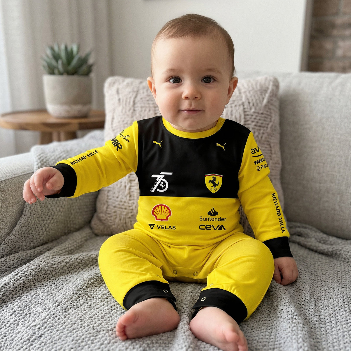 Baby sitting on sofa in Ferrari 75 Years onesie jumpsuit, yellow black F1 race suit with sponsor logos
