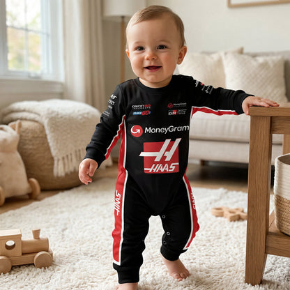 Baby standing in Haas 2025 F1 racing onesie smiling in living room with wooden toys