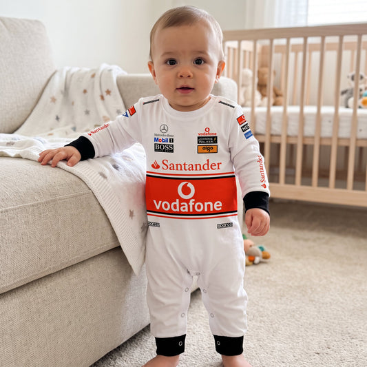 Baby wearing McLaren 2008 racing onesie standing in nursery white F1 jumpsuit with Vodafone band