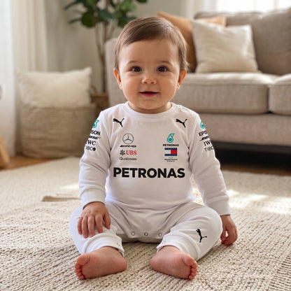 Baby sitting on a rug wearing white 2018 Mercedes AMG Petronas F1 onesie in a living room