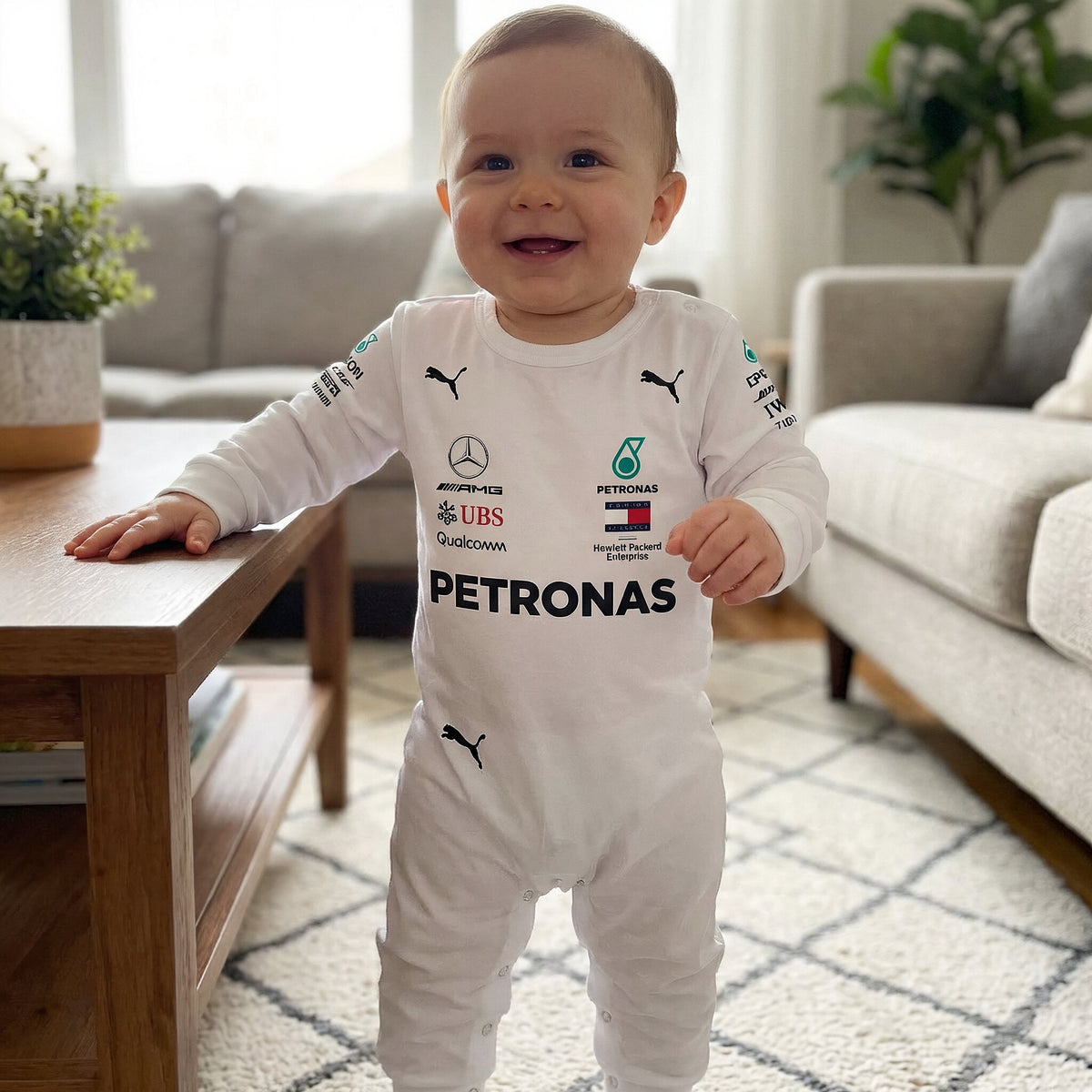 Baby standing and smiling in white 2018 Mercedes AMG Petronas F1 onesie in a living room
