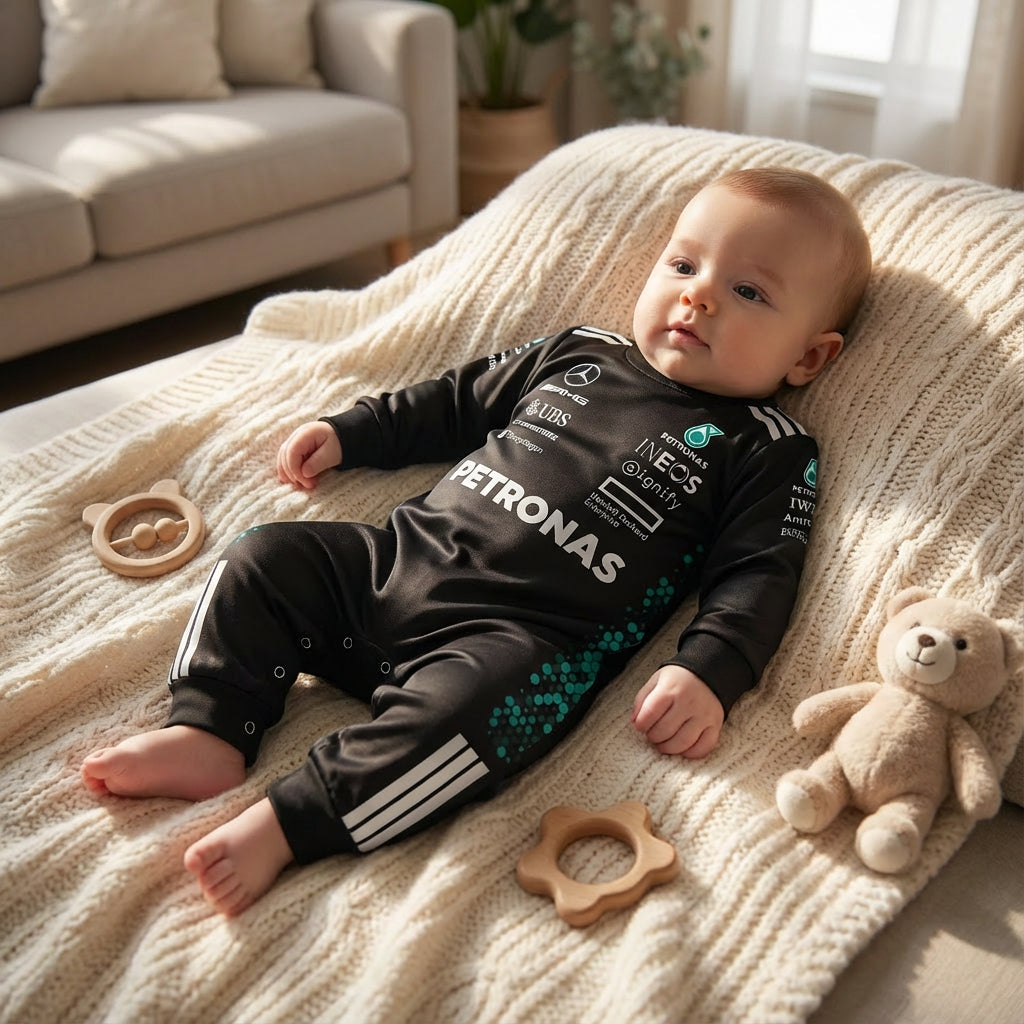 toddler wearing a formula one themed mercedes amg onesie jumpsuit laying on a couch with a knitted blanket