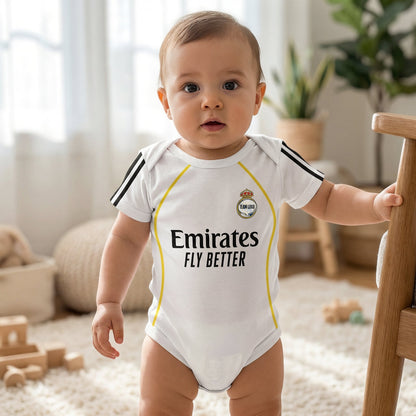 baby wearing Real Madrid 2025-26 white bodysuit standing in bright nursery holding wooden crib rail