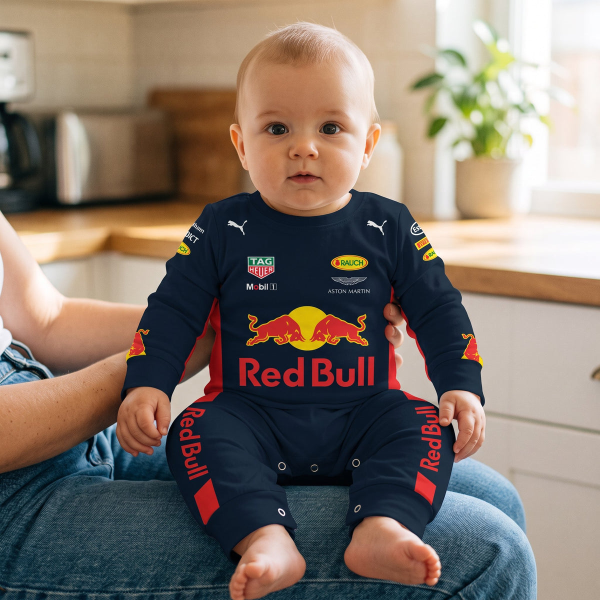 Baby in Red Bull 2017 Classic F1 romper sitting on parent lap in kitchen navy racing suit onesie