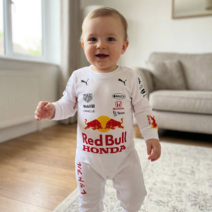 Baby in living room wearing Red Bull Honda F1 racing onesie jumpsuit with sponsor logos smiling
