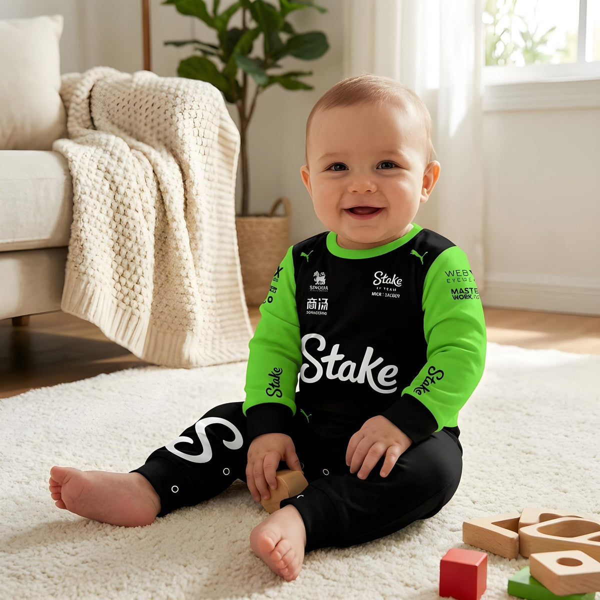 Baby sitting wearing Stake Kick 2025 jumpsuit onesie holding toy black green F1 baby romper in nursery